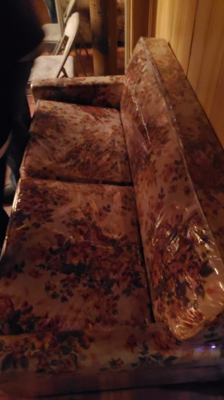 an old floral sofa in a shiny plastic case